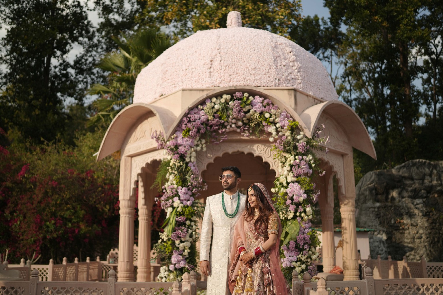 A couple before an architectural floral mandap