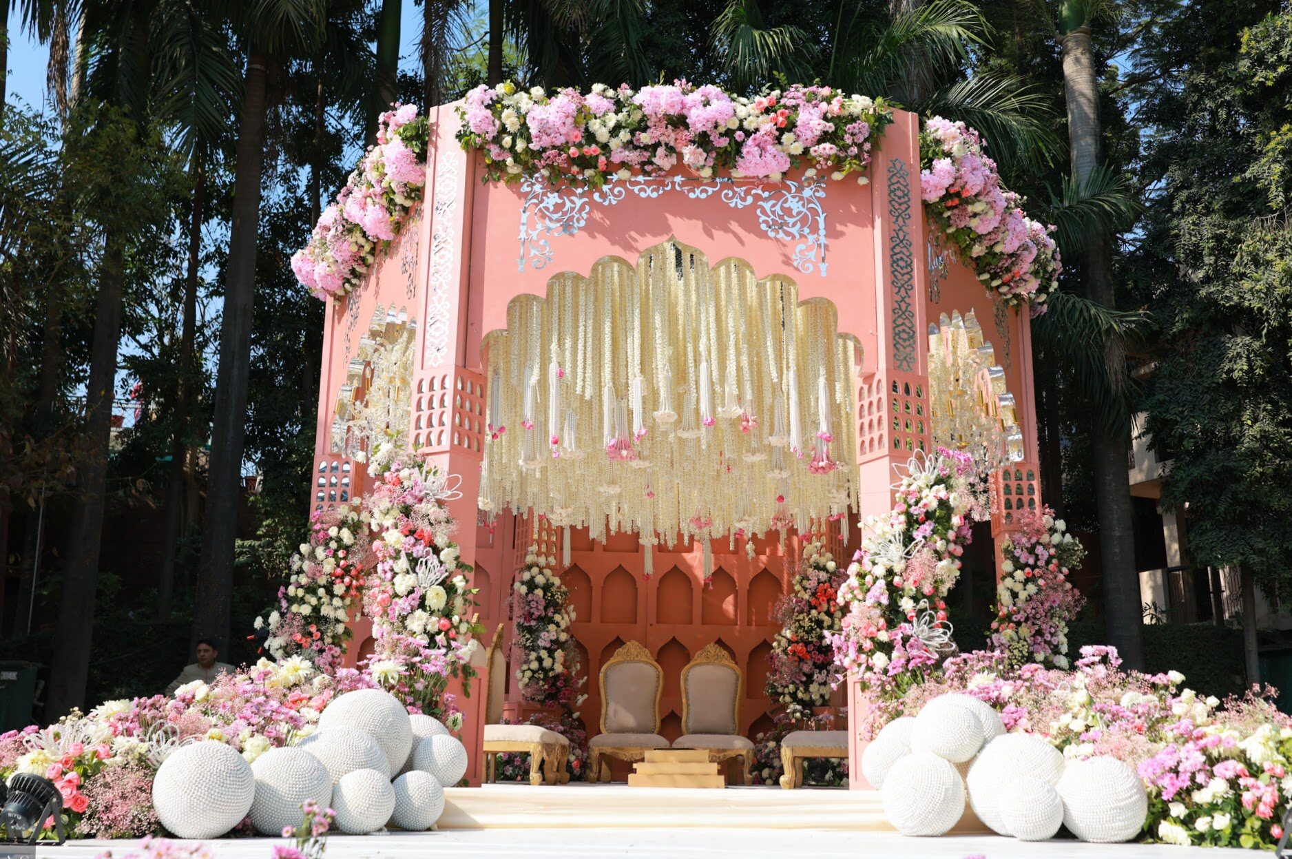 A coral architectural mandap layered with pink and white florals